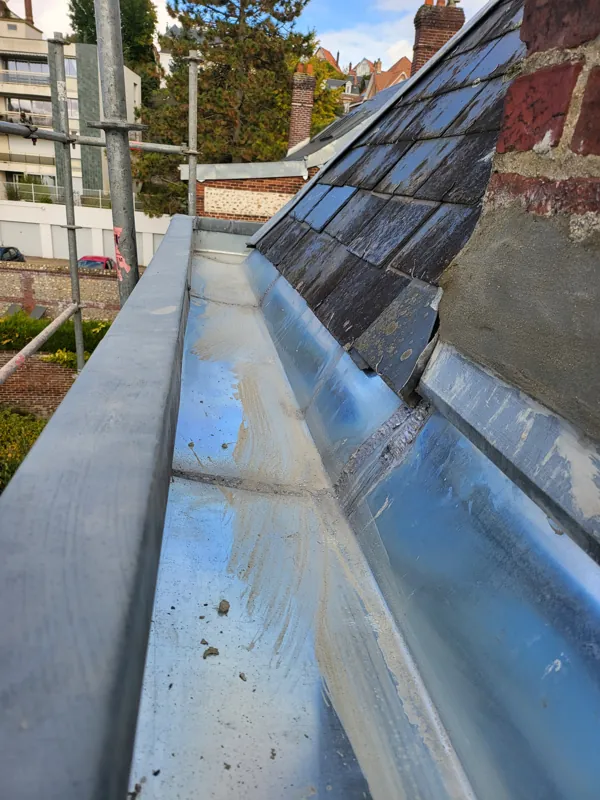 Chéneau en zinc neuf le long d'une toiture en ardoise