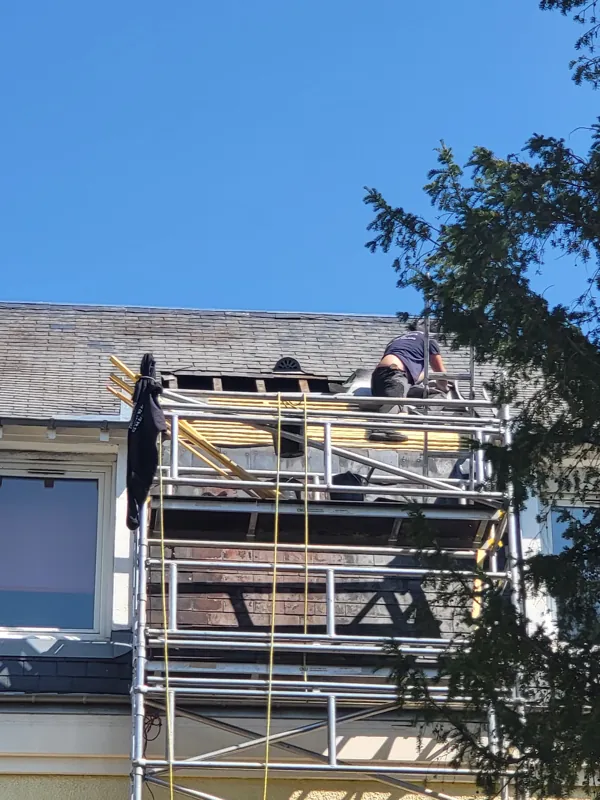 Couvreurs sur une toiture en ardoise, échafaudage en façade
