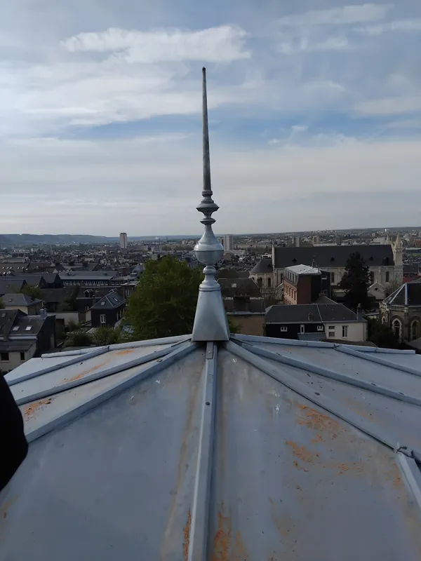Épi de faîtage en zinc sur un toit, vue sur les toits de la ville