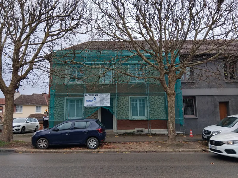 Façade de maison sous échafaudage bâché, côté rue