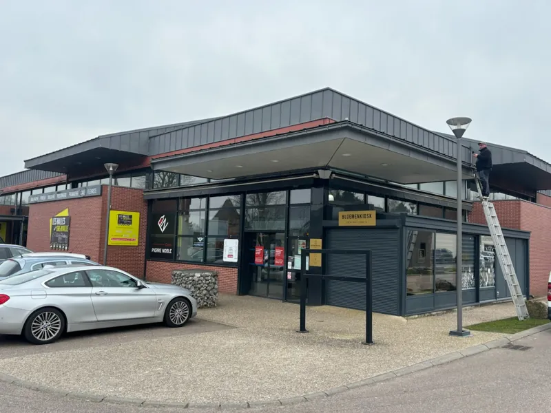 Couvreur sur échelle contre la façade d'un local commercial
