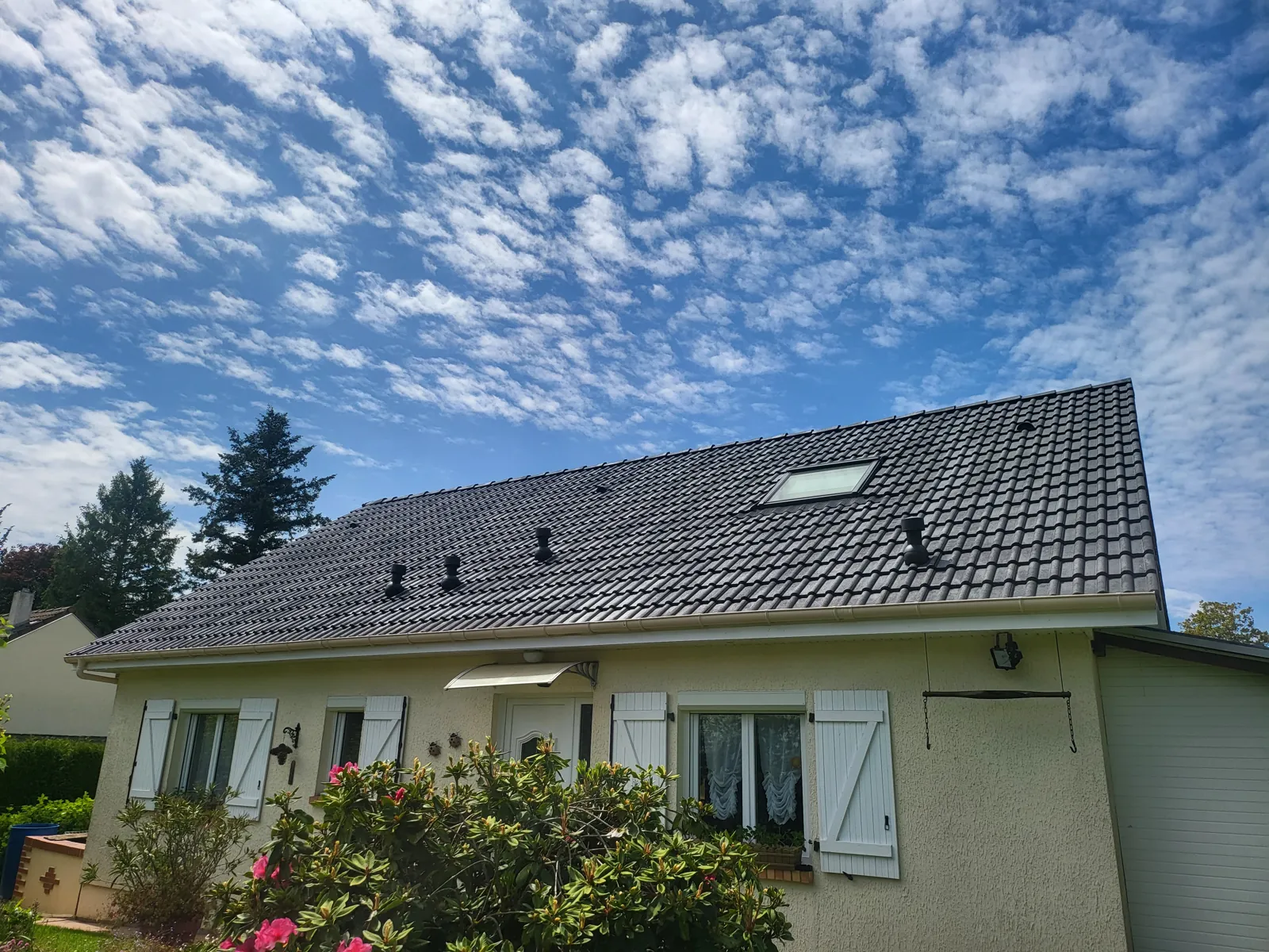 Maison avec une toiture en tuiles refaite et une fenêtre de toit