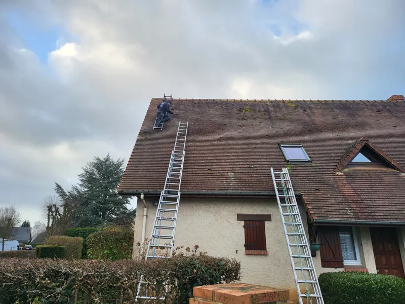 Maison à toiture en tuiles, deux échelles posées contre la façade