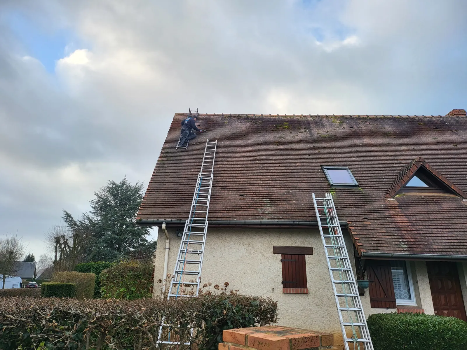 Maison à toiture en tuiles, deux échelles posées contre la façade
