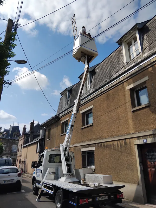 Nacelle élévatrice déployée dans une rue étroite, le long d'une façade