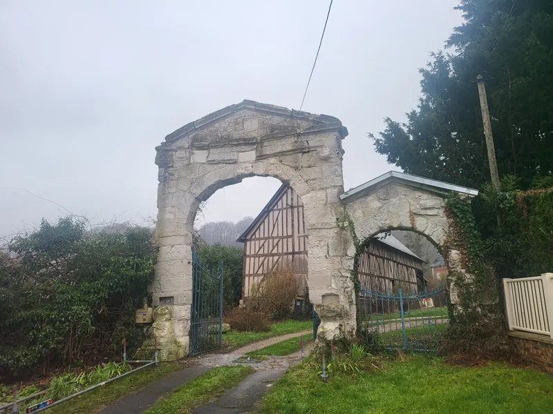 Portail ancien en pierre et ferme à colombages par temps de brume
