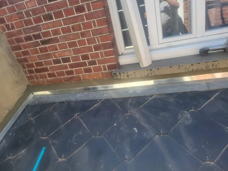 Relevé en zinc au pied d'une façade en brique sur un toit plat
