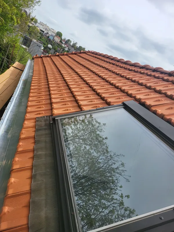 Fenêtre de toit neuve sur une toiture en tuiles rouges